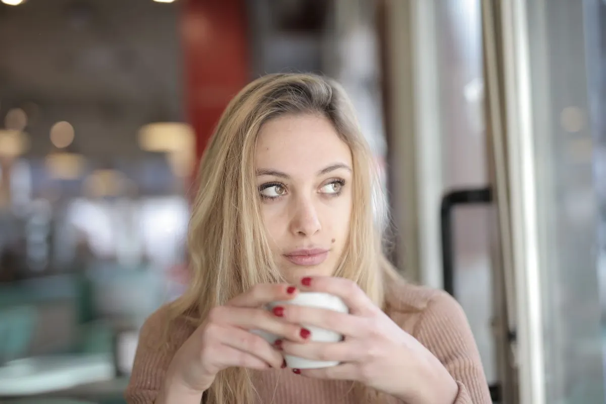 A woman looking thoughtful over a cup of coffee