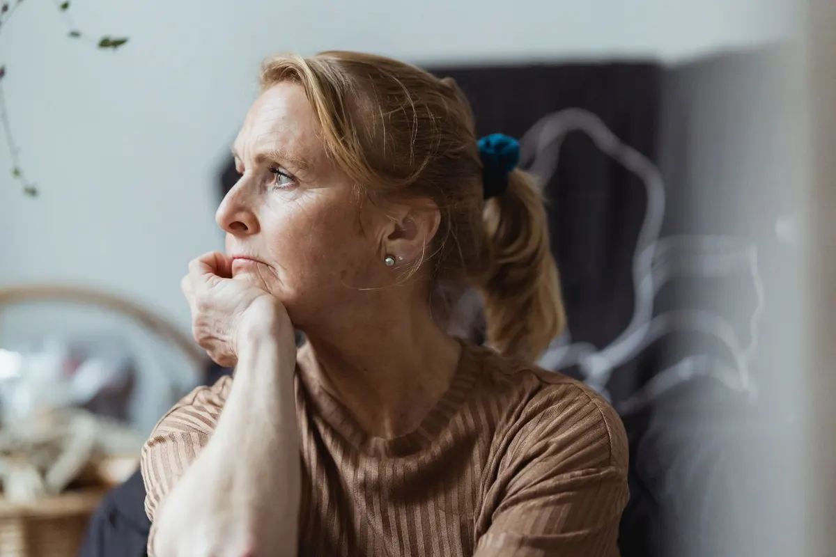 A woman in her fifties looking thoughtful, weighing a decision