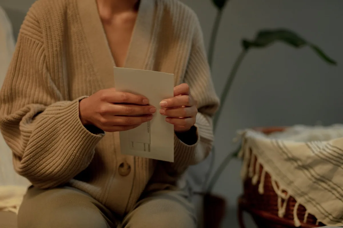 A woman in a warm sweater reading a letter at home