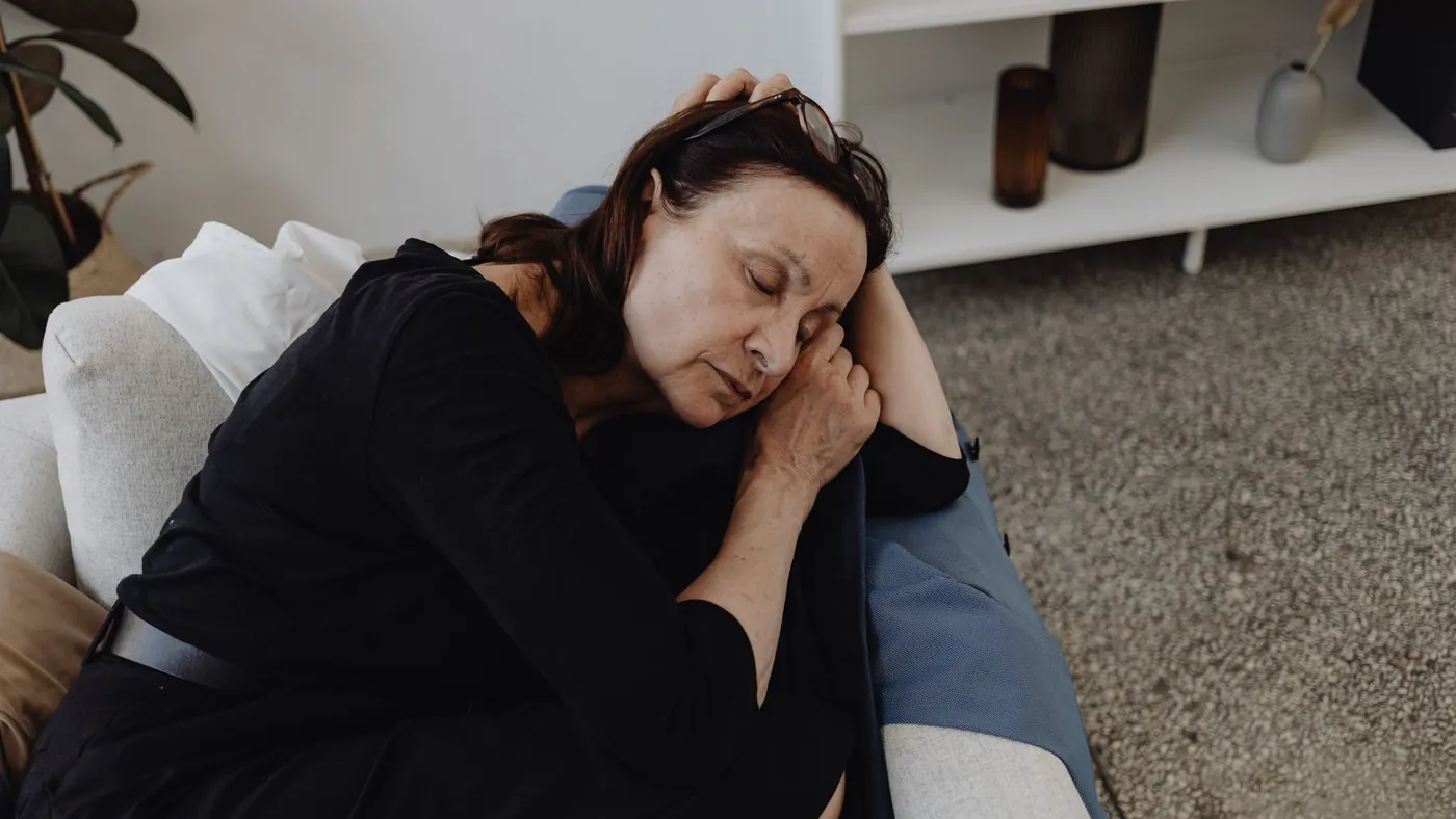 A tired woman resting on the sofa with her eyes closed