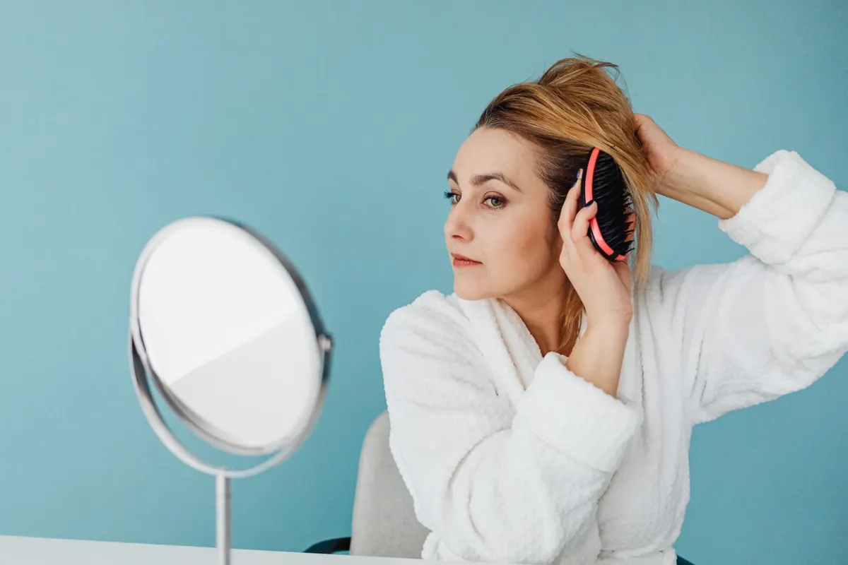 A woman brushing her hair at a mirror