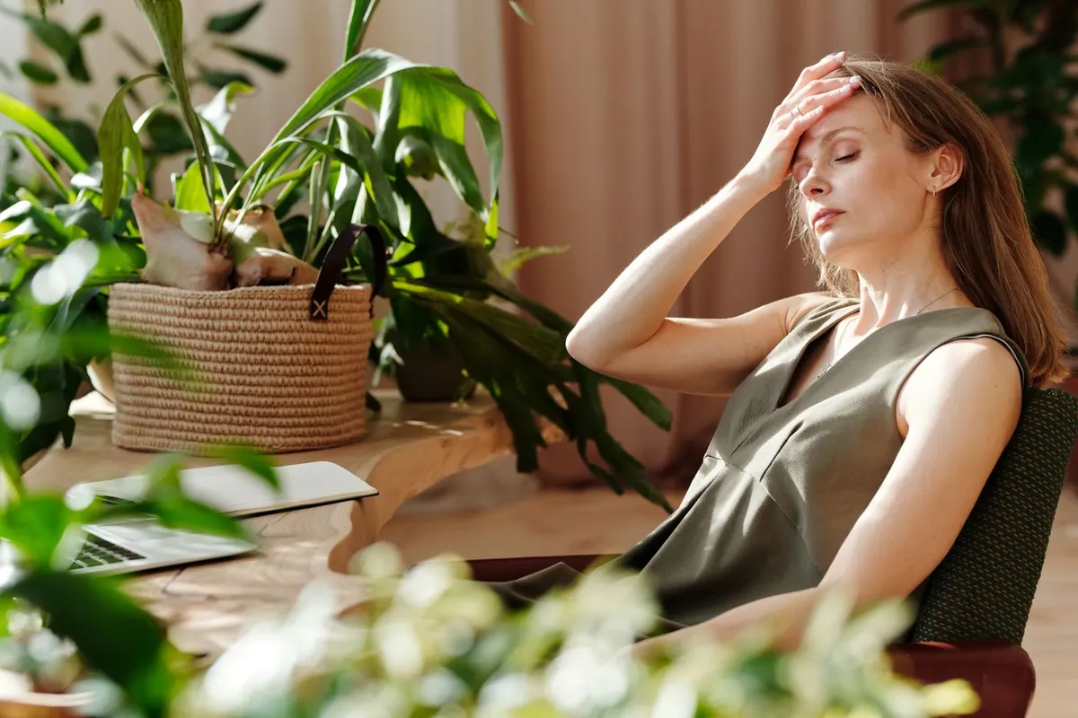 A woman resting her hand against her head at her desk