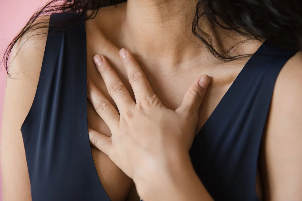 A woman pausing calmly, her hand resting on her chest