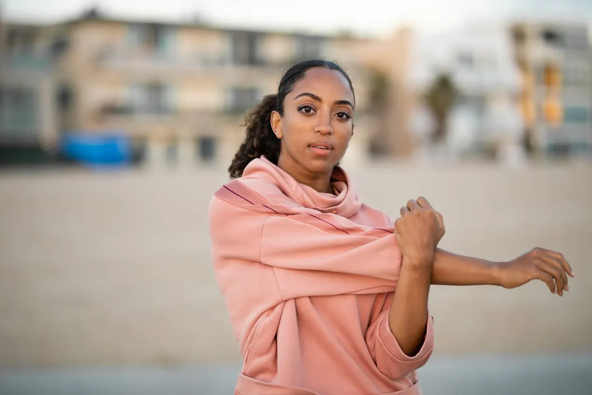 A woman in her forties stretching her arm outdoors