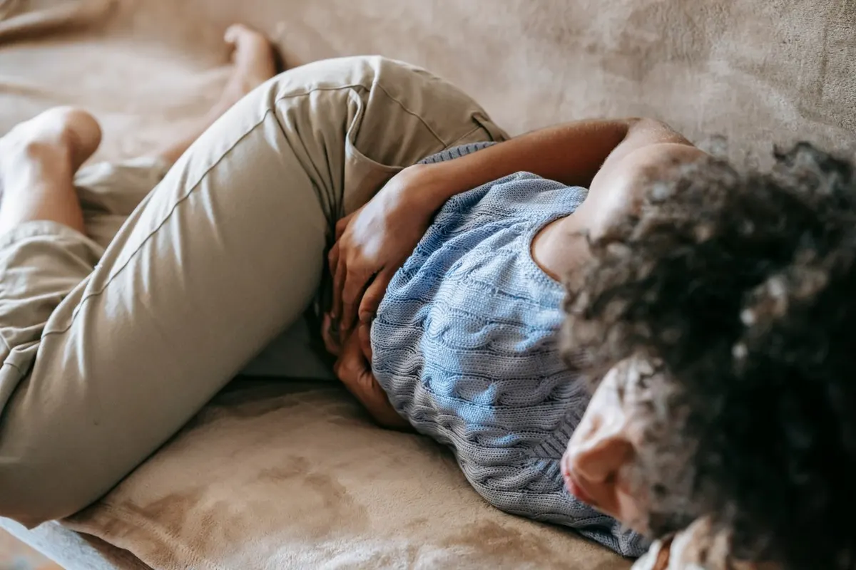 A woman resting on the sofa with a hand on her stomach