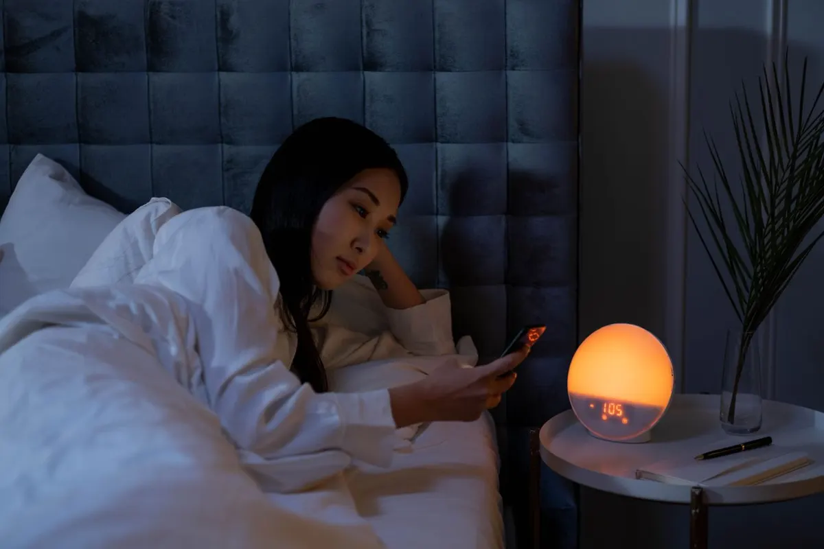 A woman lying awake in bed at night looking at her phone