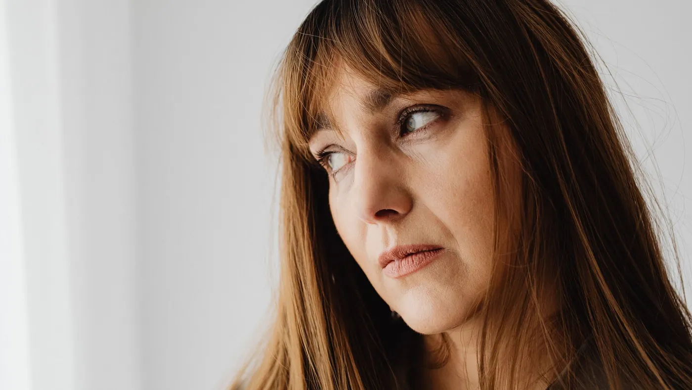A woman in her forties looking thoughtful