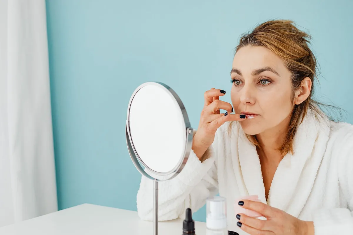 A woman looking closely at her skin in a mirror